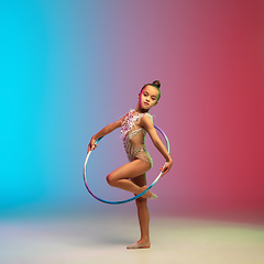 Image showing Little caucasian girl, rhytmic gymnast training, performing isolated on gradient blue-red studio background in neon