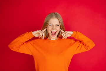 Image showing Portrait of young caucasian woman with bright emotions isolated on red studio background