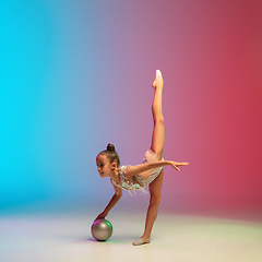 Image showing Little caucasian girl, rhytmic gymnast training, performing isolated on gradient blue-red studio background in neon