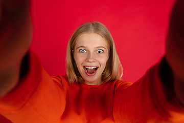 Image showing Portrait of young caucasian woman with bright emotions isolated on red studio background