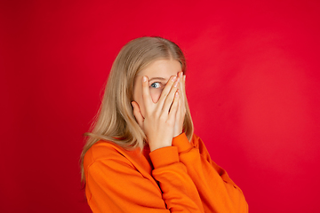 Image showing Portrait of young caucasian woman with bright emotions isolated on red studio background