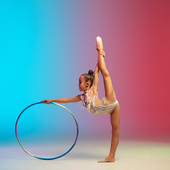 Image showing Little caucasian girl, rhytmic gymnast training, performing isolated on gradient blue-red studio background in neon