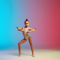 Image showing Little caucasian girl, rhytmic gymnast training, performing isolated on gradient blue-red studio background in neon