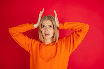 Image showing Portrait of young caucasian woman with bright emotions isolated on red studio background