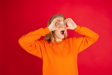 Image showing Portrait of young caucasian woman with bright emotions isolated on red studio background