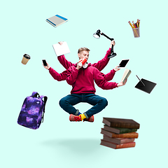 Image showing Handsome multi-armed student levitating isolated on blue studio background with equipment