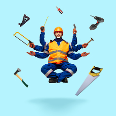 Image showing Handsome multi-armed builder levitating isolated on blue studio background with equipment