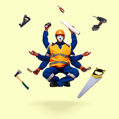 Image showing Handsome multi-armed builder levitating isolated on yellow studio background with equipment