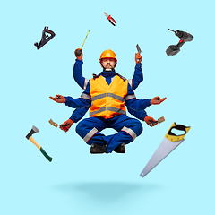 Image showing Handsome multi-armed builder levitating isolated on blue studio background with equipment