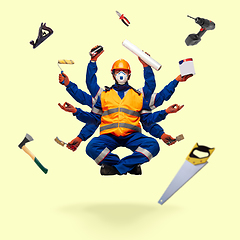 Image showing Handsome multi-armed builder levitating isolated on yellow studio background with equipment