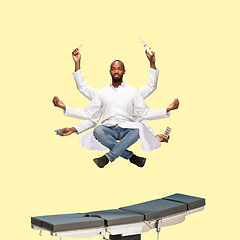 Image showing Handsome multi-armed doctor levitating isolated on yellow studio background with equipment