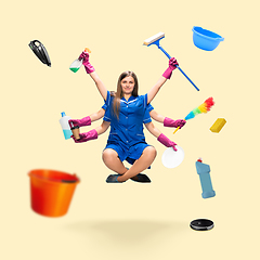 Image showing Handsome multi-armed housemaid levitating isolated on yellow studio background with equipment