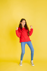 Image showing Portrait of young caucasian teen girl with bright emotions isolated on yellow studio background