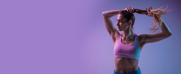 Image showing Young sportive woman training isolated on gradient studio background in neon light. athletic and graceful