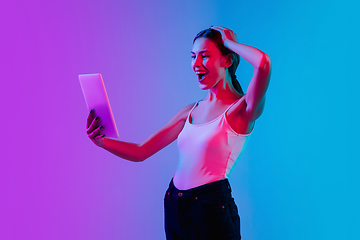 Image showing Young caucasian woman\'s portrait on gradient blue-purple studio background in neon light