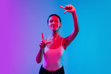 Image showing Young caucasian woman\'s portrait on gradient blue-purple studio background in neon light