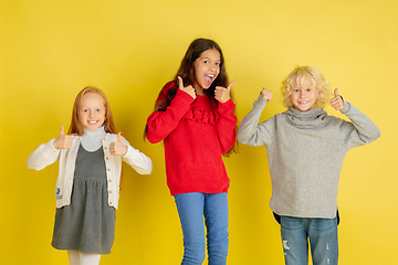 Image showing Portrait of little caucasian children with bright emotions isolated on yellow studio background