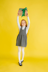 Image showing Giving and getting presents on Christmas holidays. Teen girl having fun isolated on yellow studio background