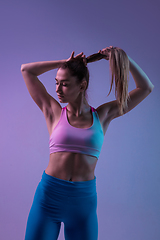 Image showing Young sportive woman training isolated on gradient studio background in neon light. athletic and graceful