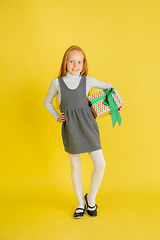 Image showing Giving and getting presents on Christmas holidays. Teen girl having fun isolated on yellow studio background