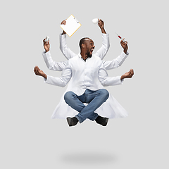 Image showing Handsome multi-armed doctor levitating isolated on grey studio background with equipment