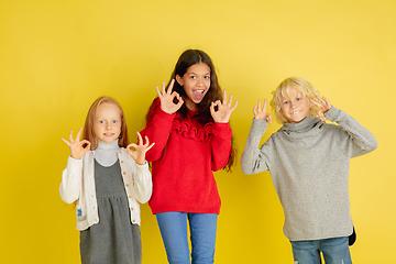 Image showing Portrait of little caucasian children with bright emotions isolated on yellow studio background