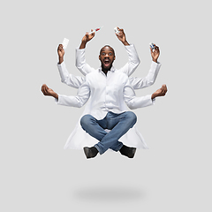 Image showing Handsome multi-armed doctor levitating isolated on grey studio background with equipment