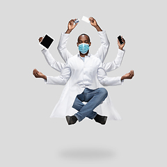 Image showing Handsome multi-armed doctor levitating isolated on grey studio background with equipment