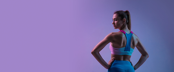 Image showing Young sportive woman training isolated on gradient studio background in neon light. athletic and graceful
