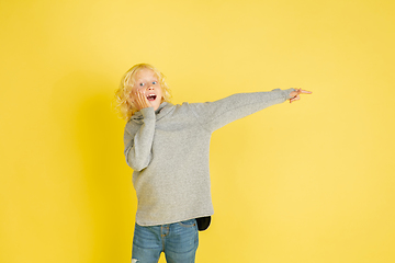 Image showing Portrait of little caucasian boy with bright emotions isolated on yellow studio background