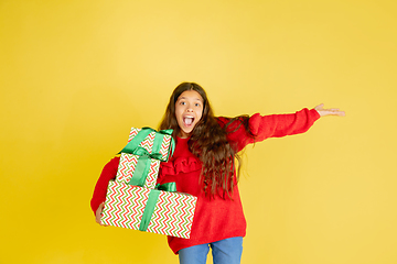 Image showing Giving and getting presents on Christmas holidays. Teen girl having fun isolated on yellow studio background