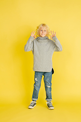 Image showing Portrait of little caucasian boy with bright emotions isolated on yellow studio background