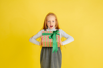 Image showing Giving and getting presents on Christmas holidays. Teen girl having fun isolated on yellow studio background