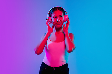 Image showing Young caucasian woman\'s portrait on gradient blue-purple studio background in neon light