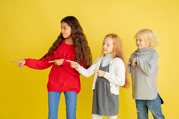 Image showing Portrait of little caucasian children with bright emotions isolated on yellow studio background