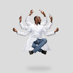 Image showing Handsome multi-armed doctor levitating isolated on grey studio background with equipment