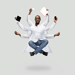 Image showing Handsome multi-armed doctor levitating isolated on grey studio background with equipment