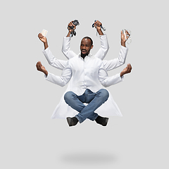 Image showing Handsome multi-armed doctor levitating isolated on grey studio background with equipment