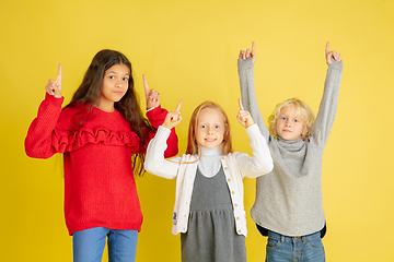 Image showing Portrait of little caucasian children with bright emotions isolated on yellow studio background