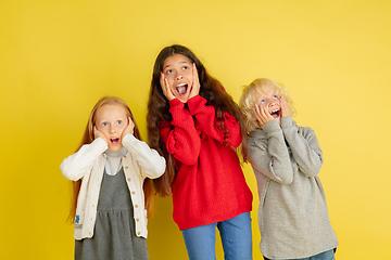 Image showing Portrait of little caucasian children with bright emotions isolated on yellow studio background