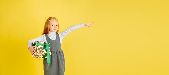 Image showing Giving and getting presents on Christmas holidays. Teen girl having fun isolated on yellow studio background