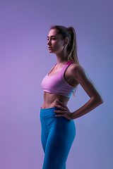 Image showing Young sportive woman training isolated on gradient studio background in neon light. athletic and graceful