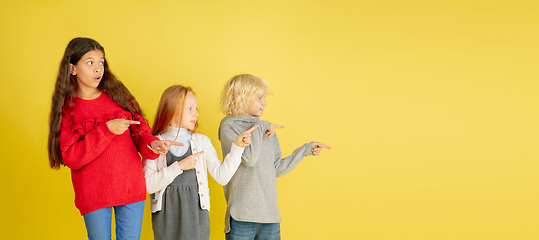 Image showing Portrait of little caucasian children with bright emotions isolated on yellow studio background