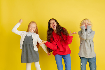 Image showing Portrait of little caucasian children with bright emotions isolated on yellow studio background