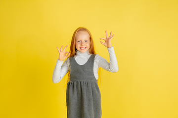 Image showing Portrait of little caucasian girl with bright emotions isolated on yellow studio background