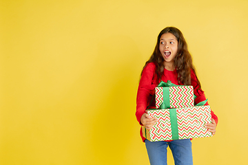 Image showing Giving and getting presents on Christmas holidays. Teen girl having fun isolated on yellow studio background