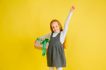 Image showing Giving and getting presents on Christmas holidays. Teen girl having fun isolated on yellow studio background