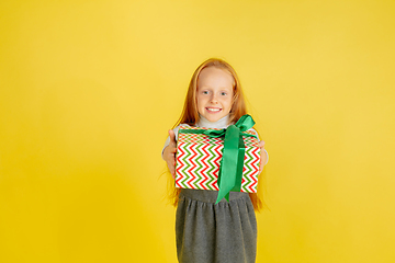 Image showing Giving and getting presents on Christmas holidays. Teen girl having fun isolated on yellow studio background