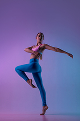 Image showing Young sportive woman training isolated on gradient studio background in neon light. athletic and graceful