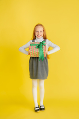 Image showing Giving and getting presents on Christmas holidays. Teen girl having fun isolated on yellow studio background